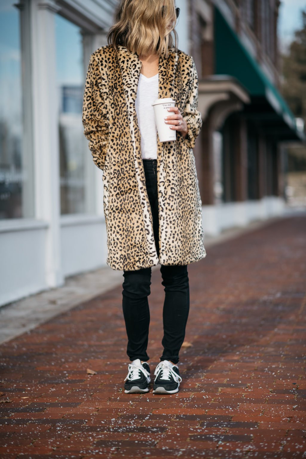 Leopard print coat, tee, black denim, sunglasses, and sneakers