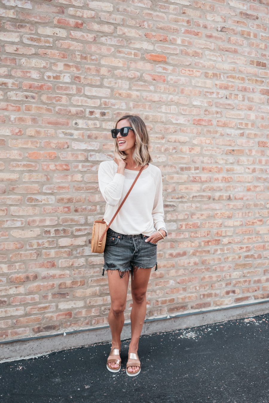 White long sleeve tee, black cut offs, sandals, straw bag, and sunnies