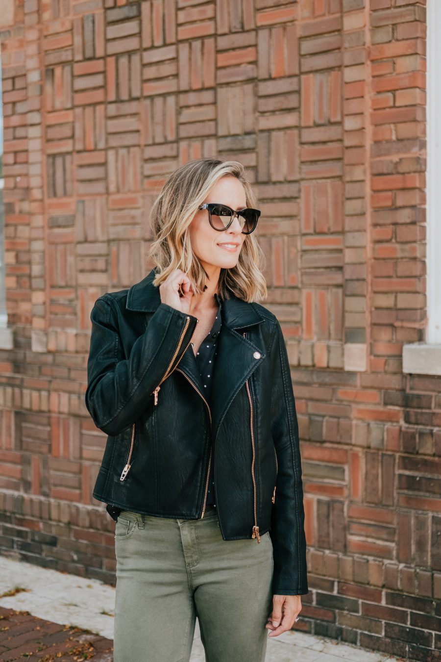 Budget friendly style: olive pants, polka dot blouse, moto jacket, and sunglasses