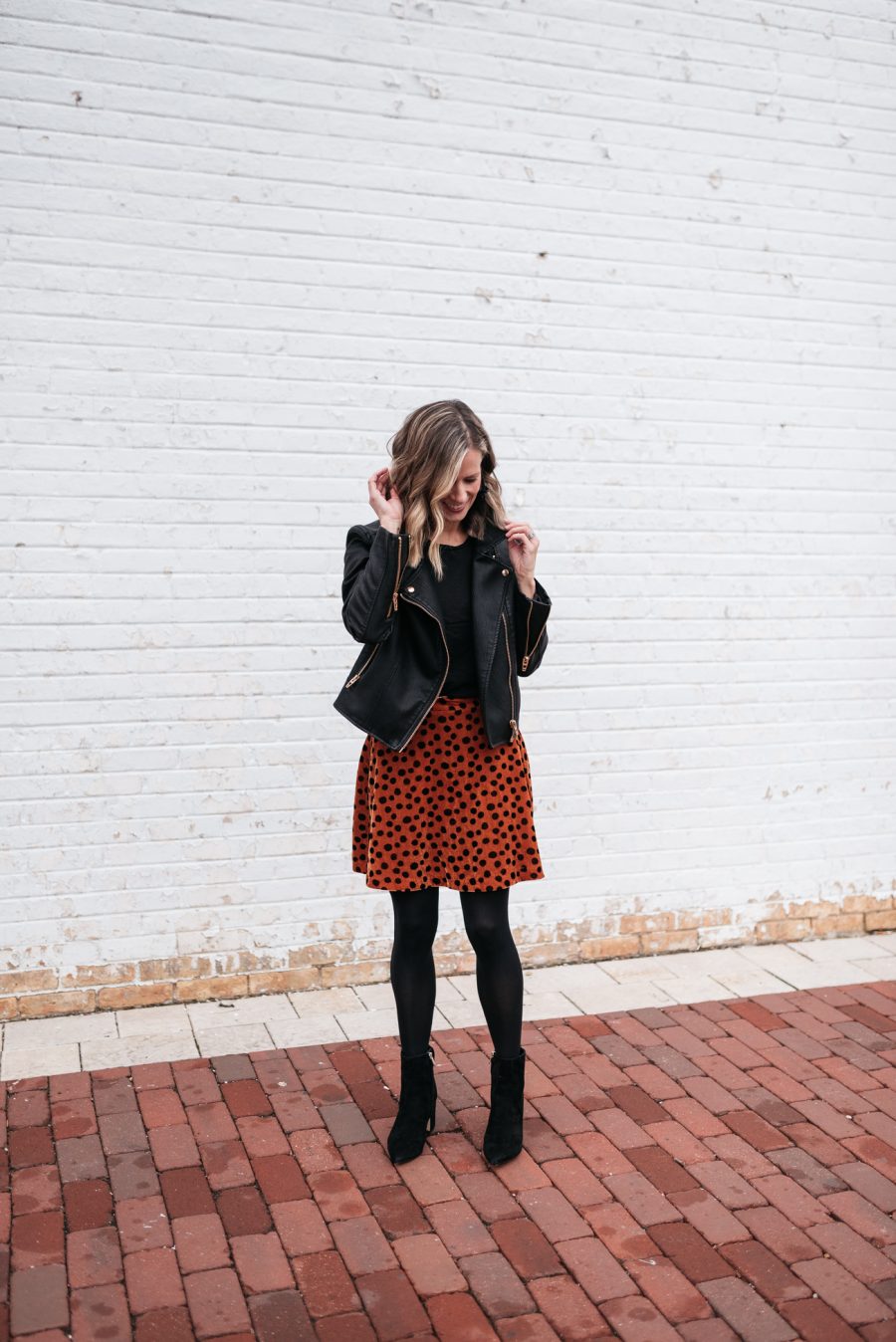 Cozy holiday party outfit: leopard skirt, tights, booties, and moto jacket