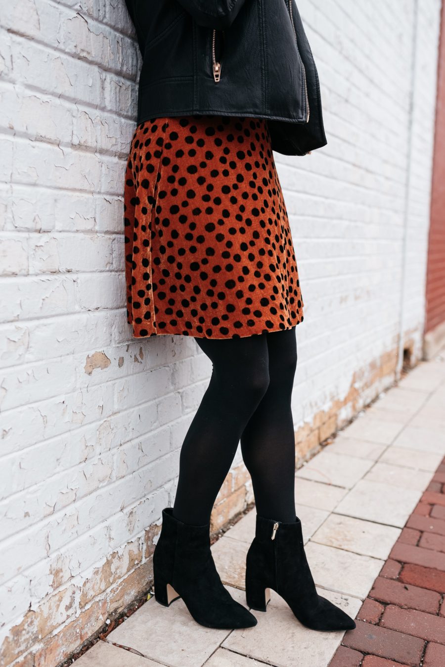 Cozy holiday party outfit: leopard skirt, tights, booties, and moto jacket
