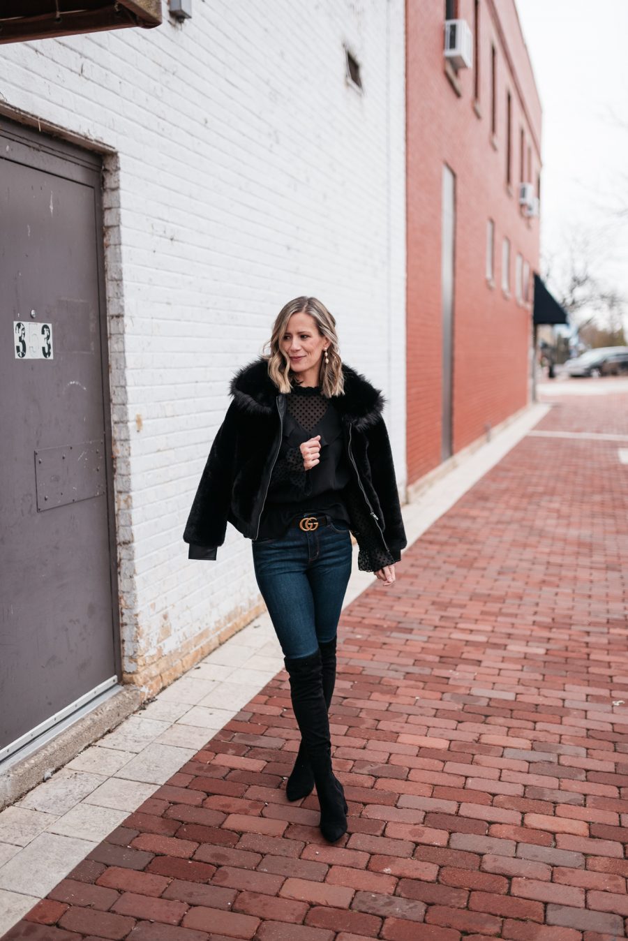 Faux fur jacket, black blouse, skinny jeans, and over the knee boots