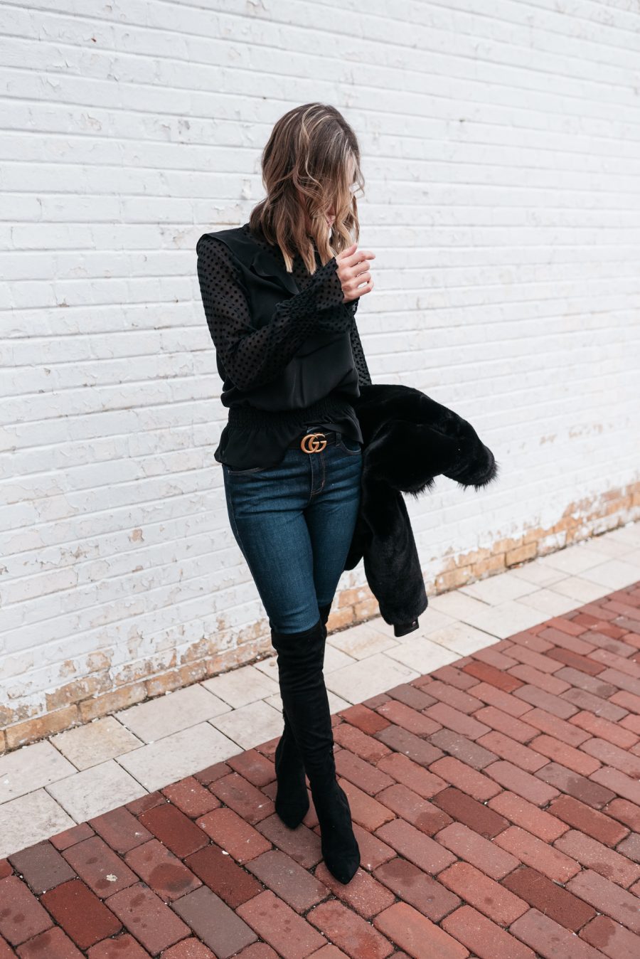 Faux fur jacket, black blouse, skinny jeans, and over the knee boots