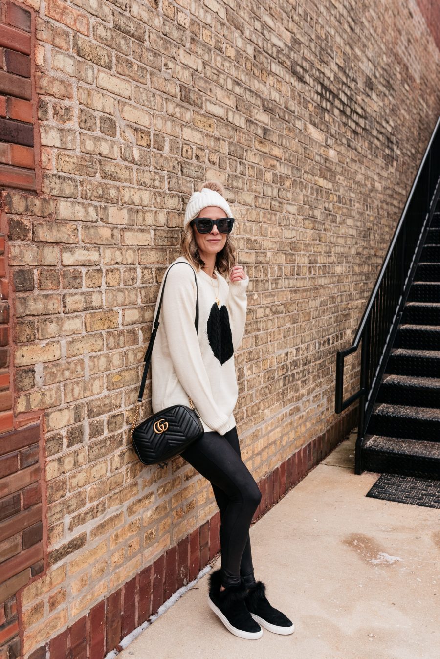 Valentine's Day Outfit: Heart sweater, faux leather leggings, sneakers, cross body, and beanie