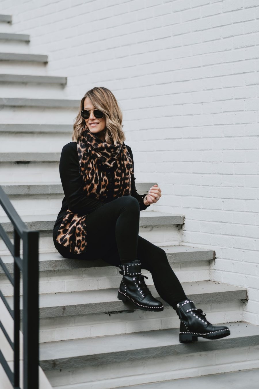 Suzanne wearing a black long sleeve tee, leggings, combat boots, and a leopard scarf