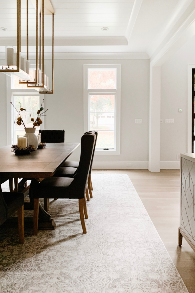 A warm and welcoming dining room of neutrals, comfortable seating, and beautiful accent lighting and art