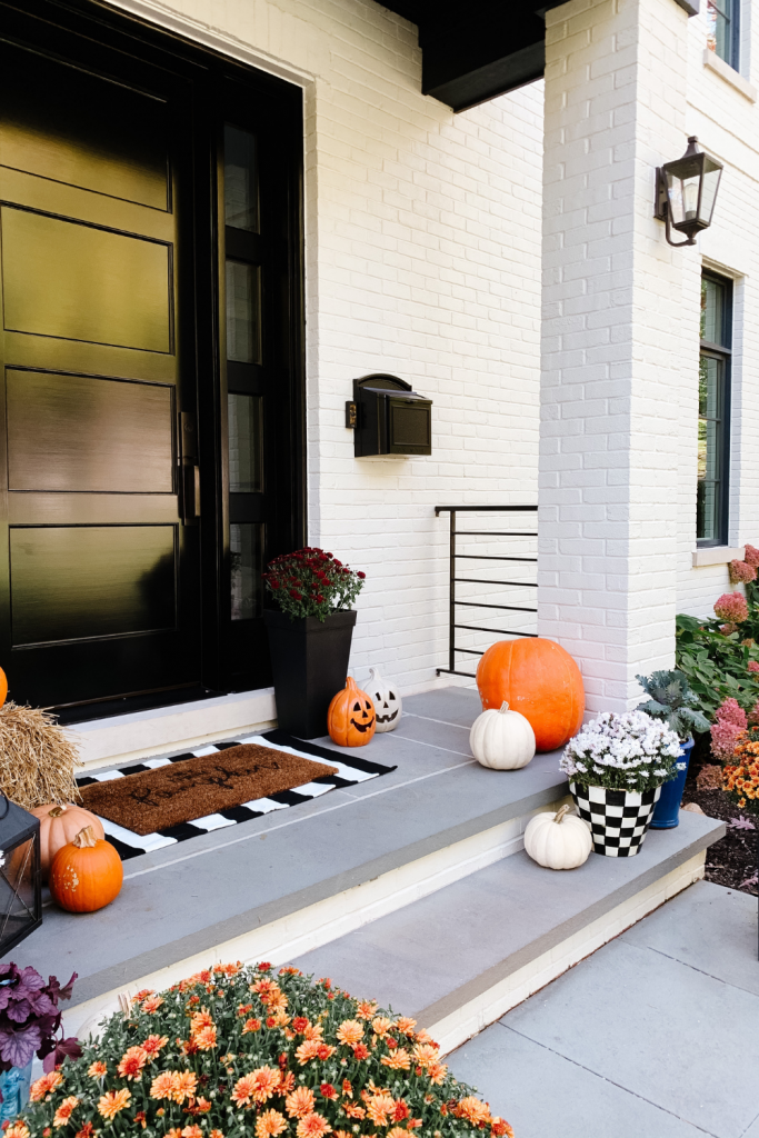 We gave our front porch a fall makeover complete with a freshly painted black door, pumpkins, mums, and a hay bail. 