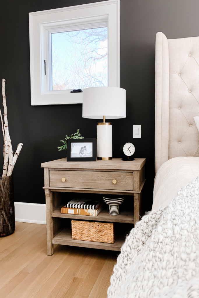 How to style a nightstand: lamp, table clock, framed pictured, basket, and books
