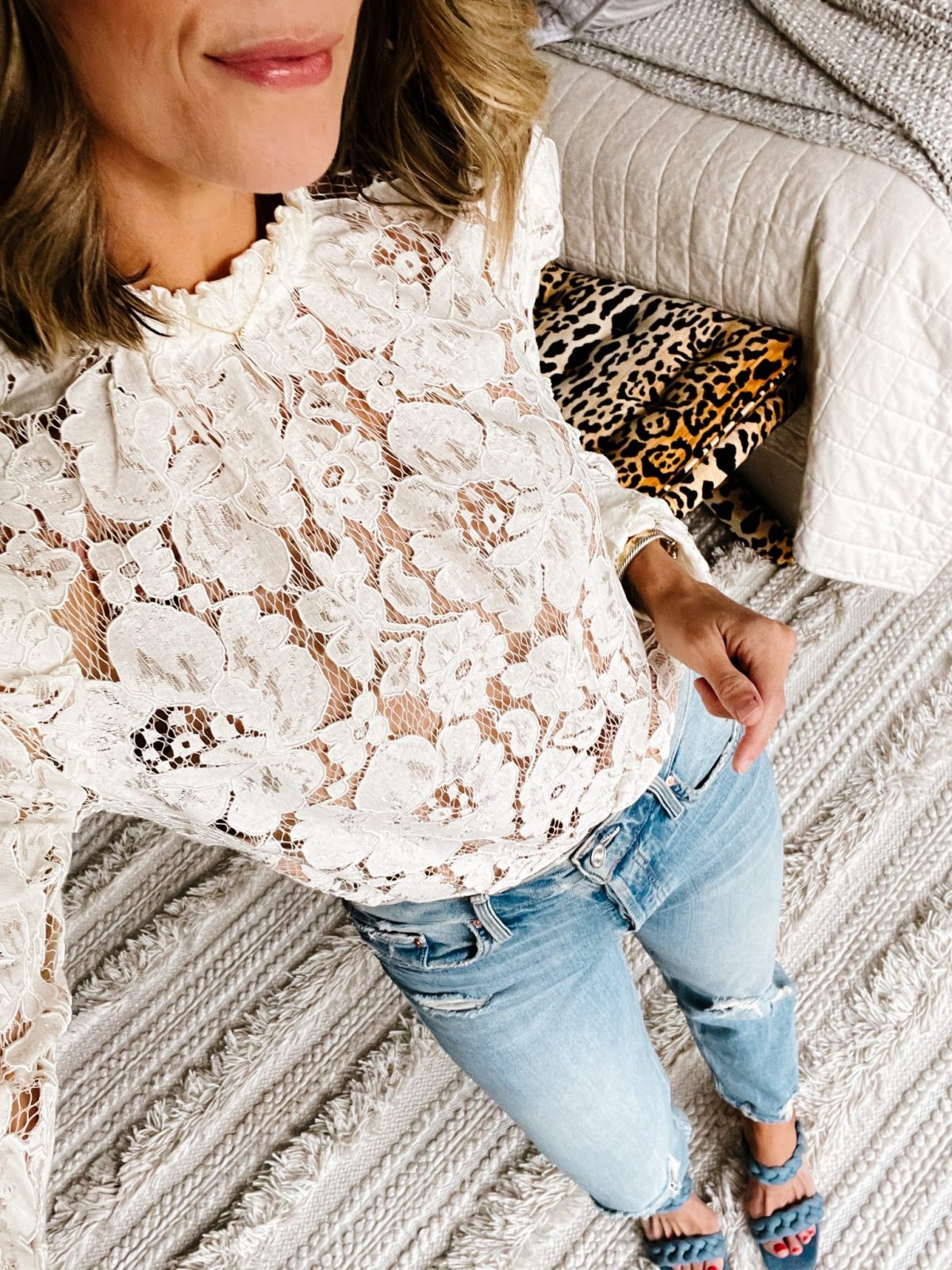 Suzanne wearing a white lace top and denim jeans