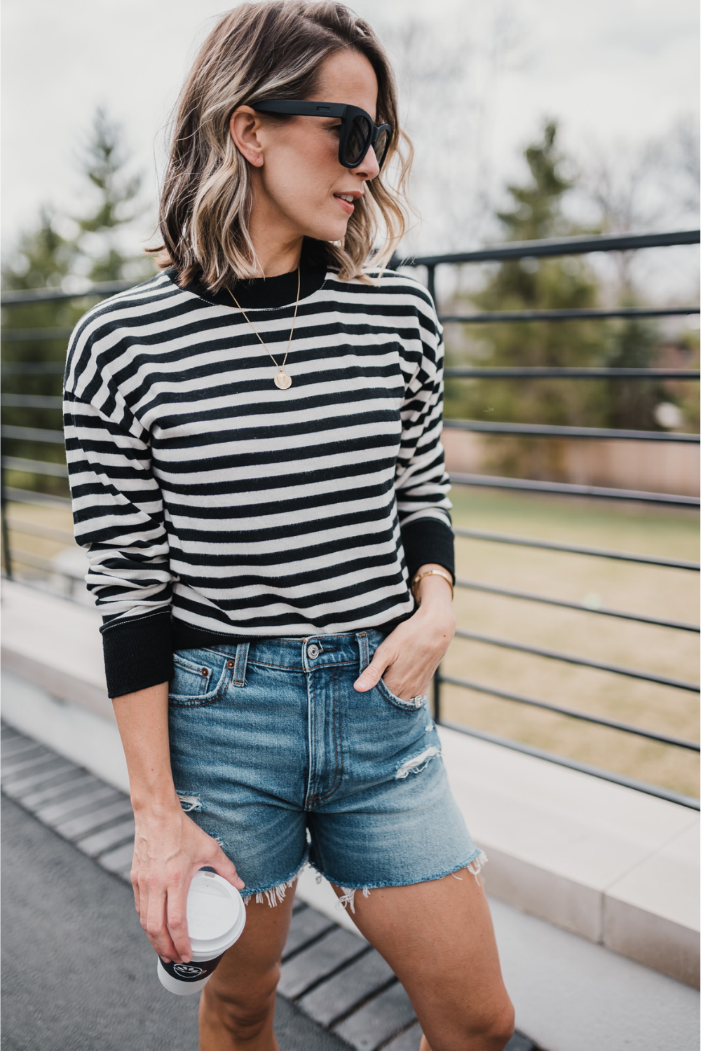 Suzanne wearing a striped long sleeve t-shirt, denim shorts, and sunglasses