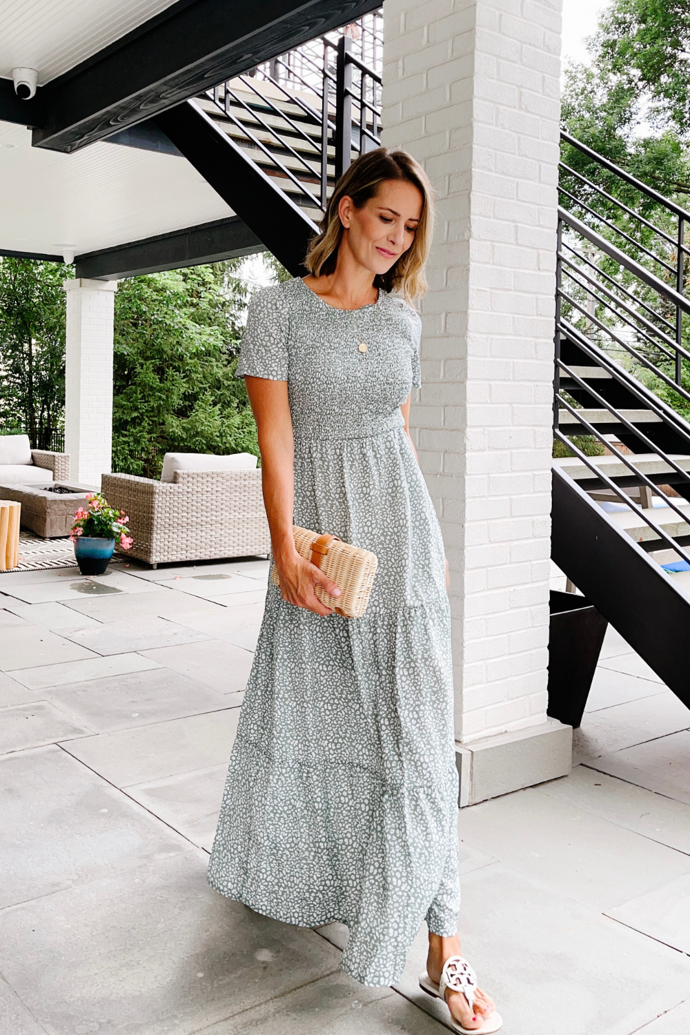 Suzanne wearing a maxi dress, ratan clutch, and sandals
