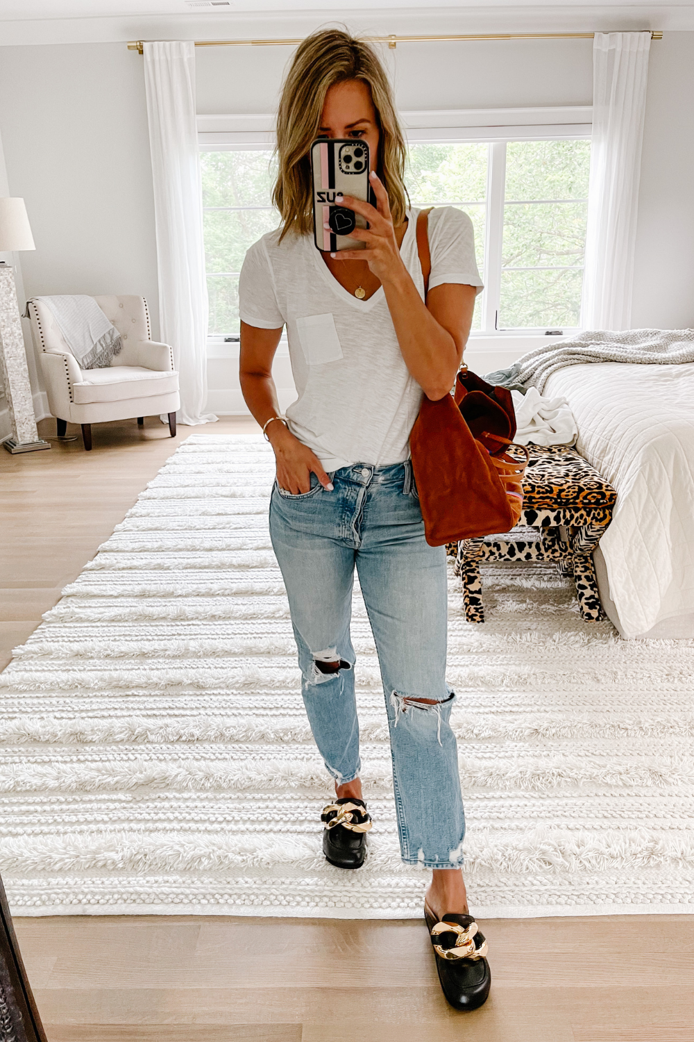 Suzanne wearing a white tee, Tomcat denim, loafers, suede bag 