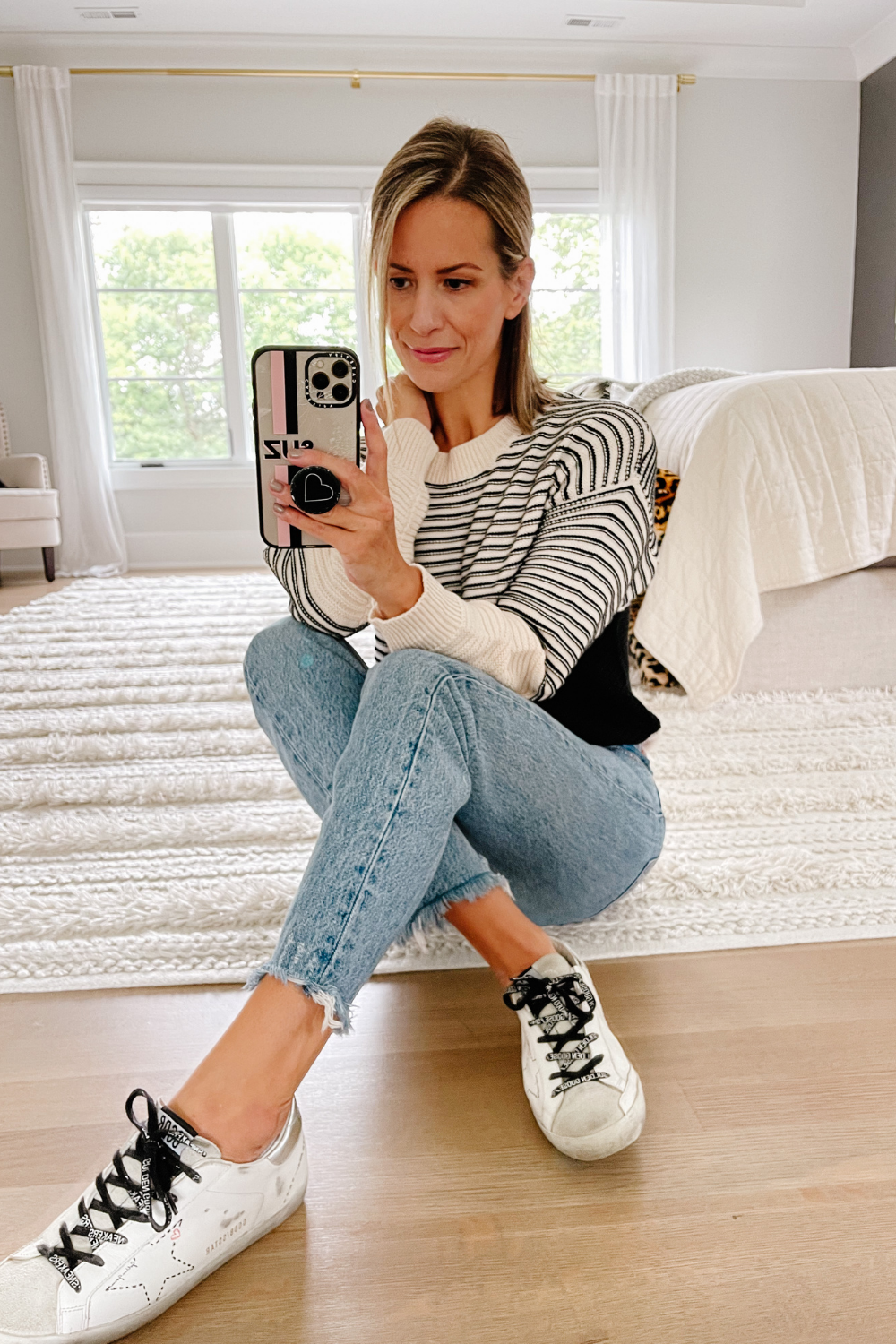 Suzanne wearing a colorblock sweater, jeans, and sneakers