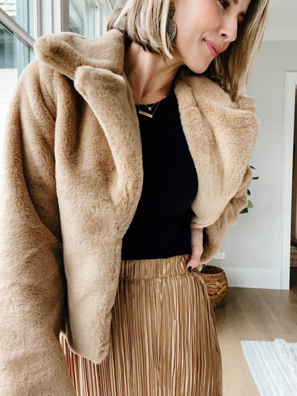 Thanksgiving outfit ideas: Suzanne wearing a faux fur jacket and gold pleated skirt
