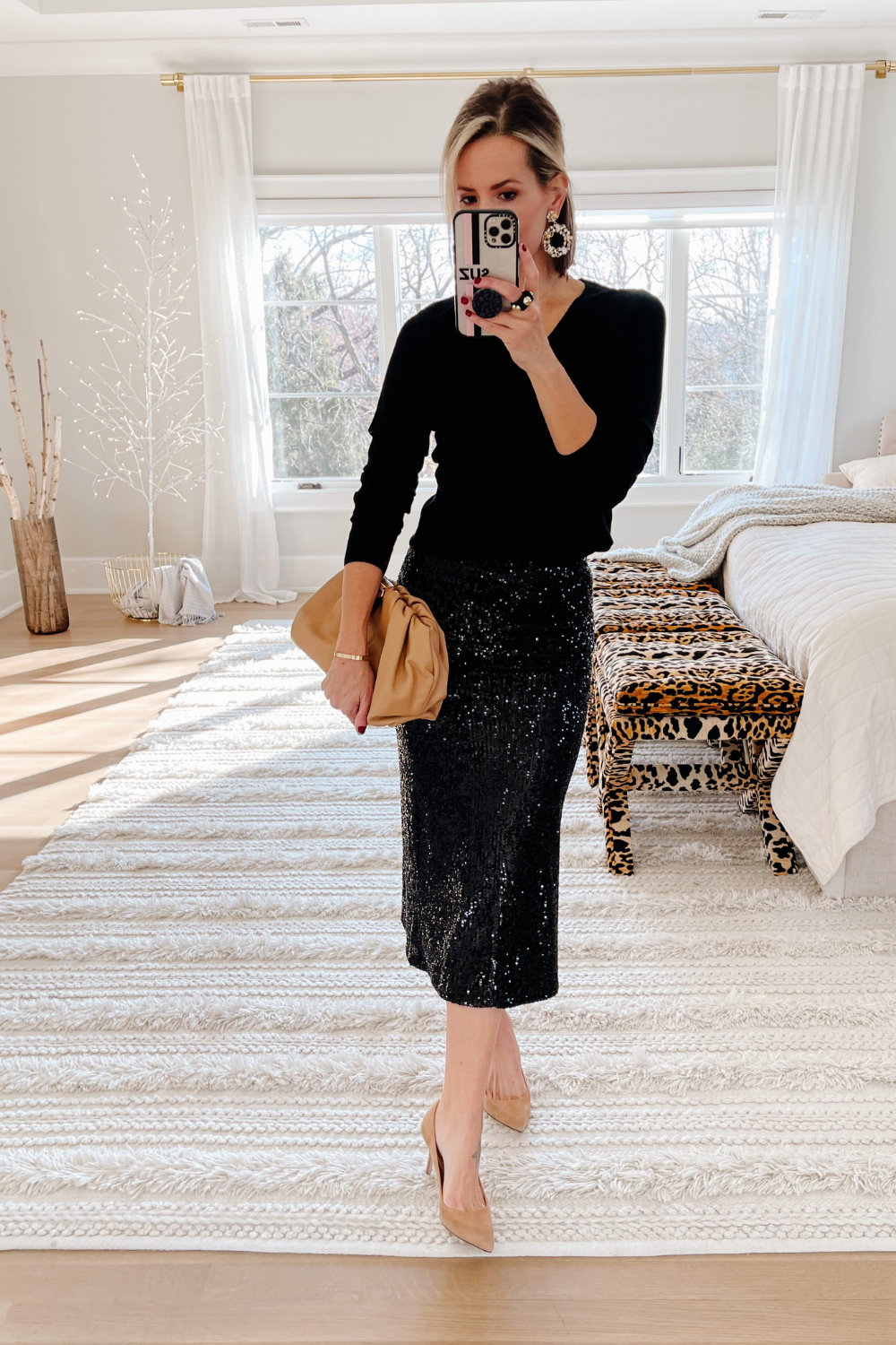 Suzanne wearing a black top, sparkly pencil skirt, nude heels and a nude clutch