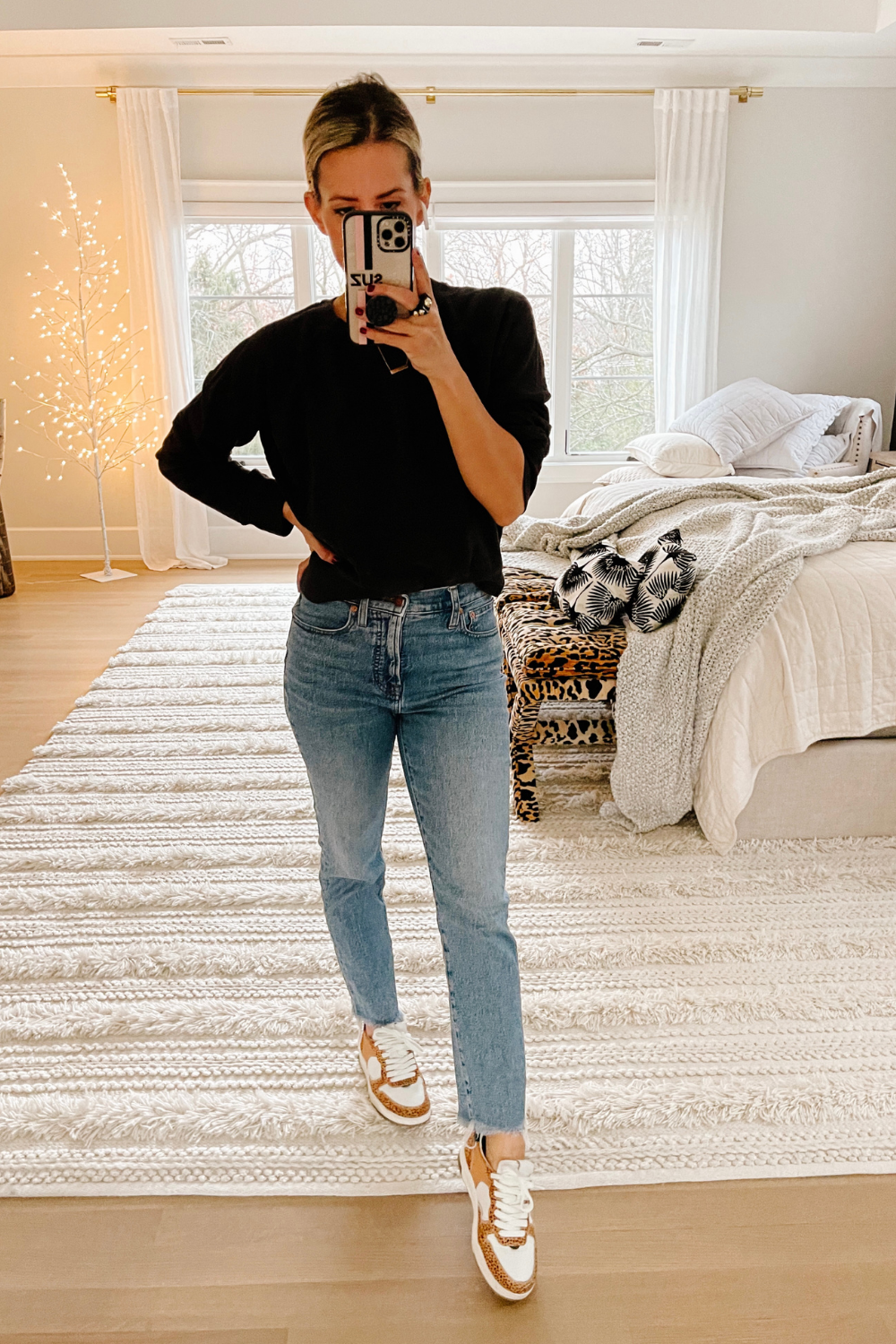 Suzanne wearing a black sweater, denim, and sneakers