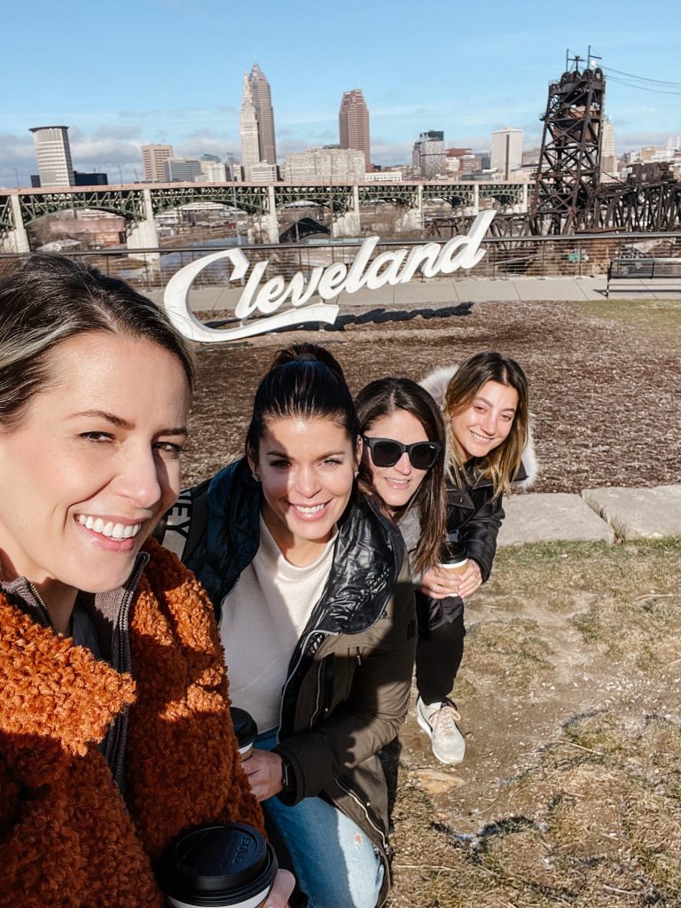 Suzanne and her friends taking a selfie in front of the "Cleveland" sign 