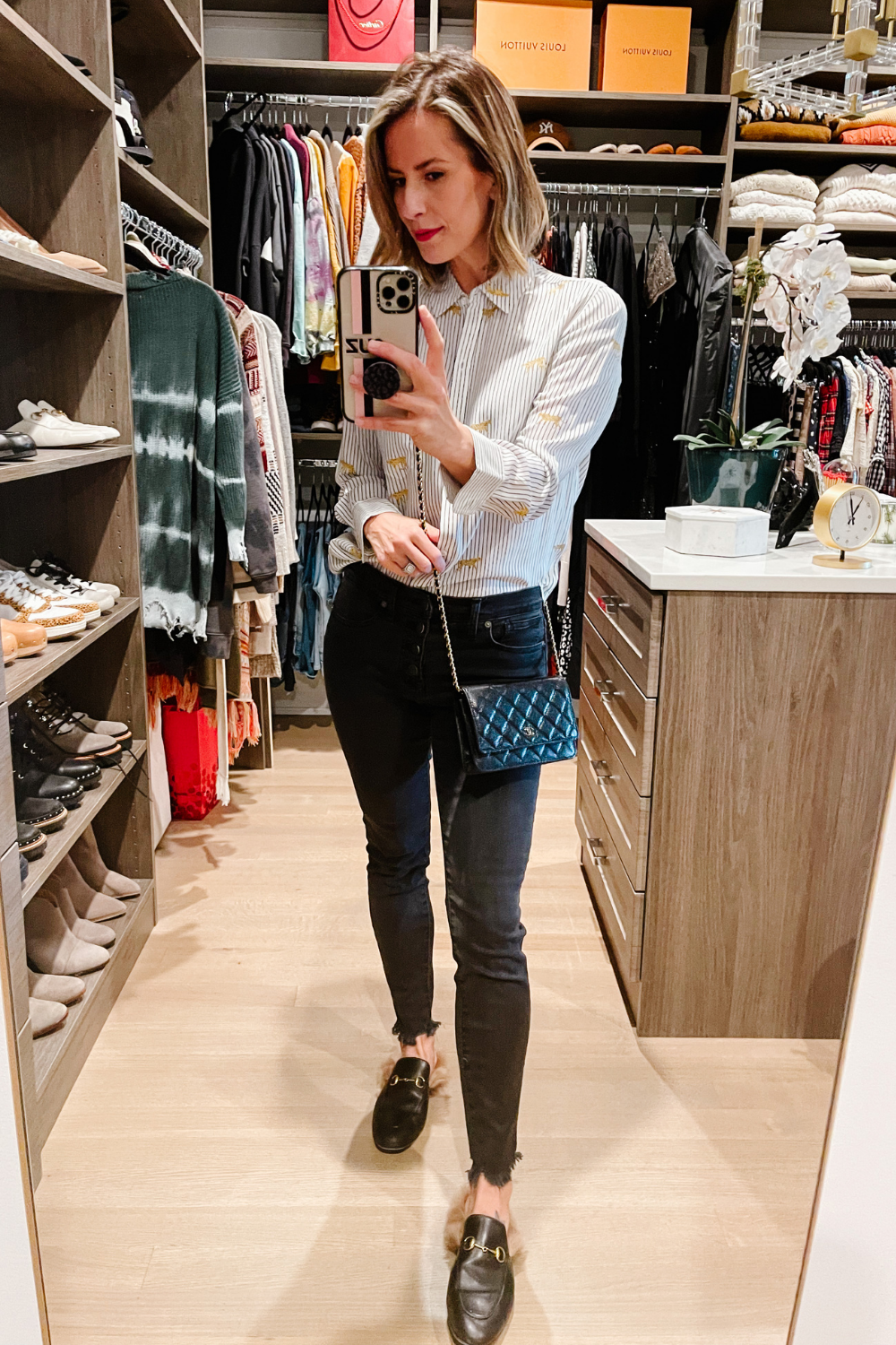 Suzanne wearing a printed button down, black denim, mules and a Chanel cross body 
