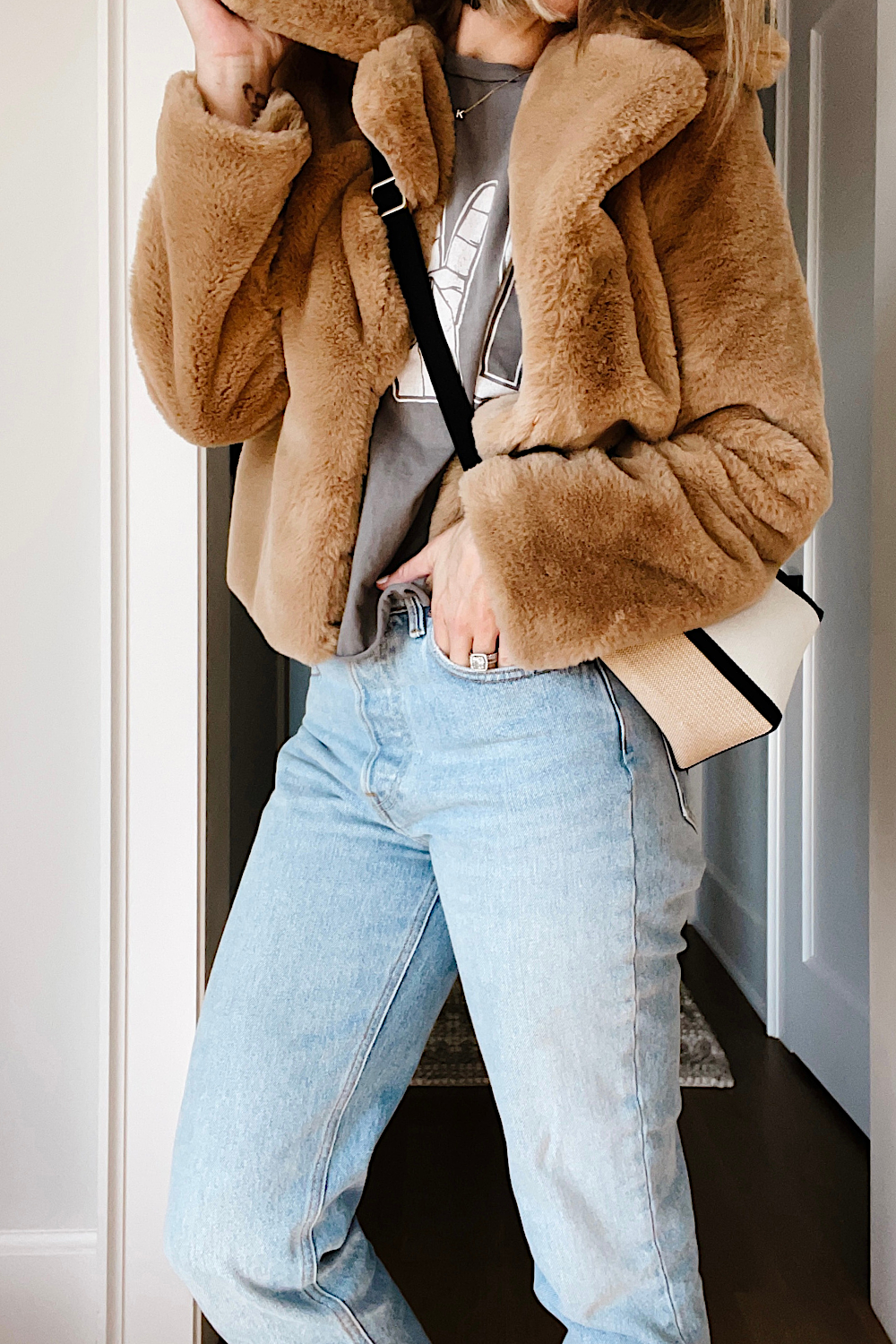 Suzanne wearing a faux fur jacket, pullover, denim jeans, and crossbody bag