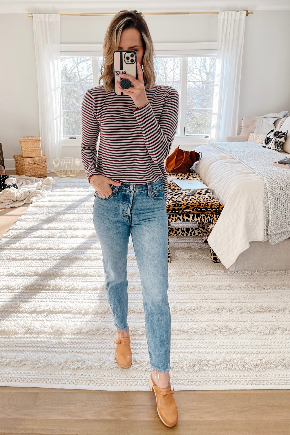 Suzanne wearing a striped turtleneck, straight leg denim, and clogs