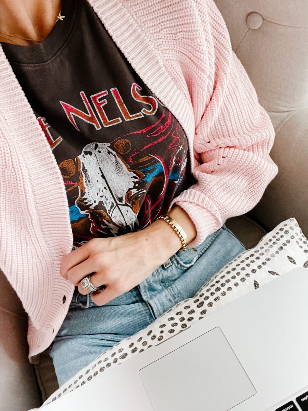 Suzanne working from home wearing a band graphic-t, a pink cardigan,, and mom jeans