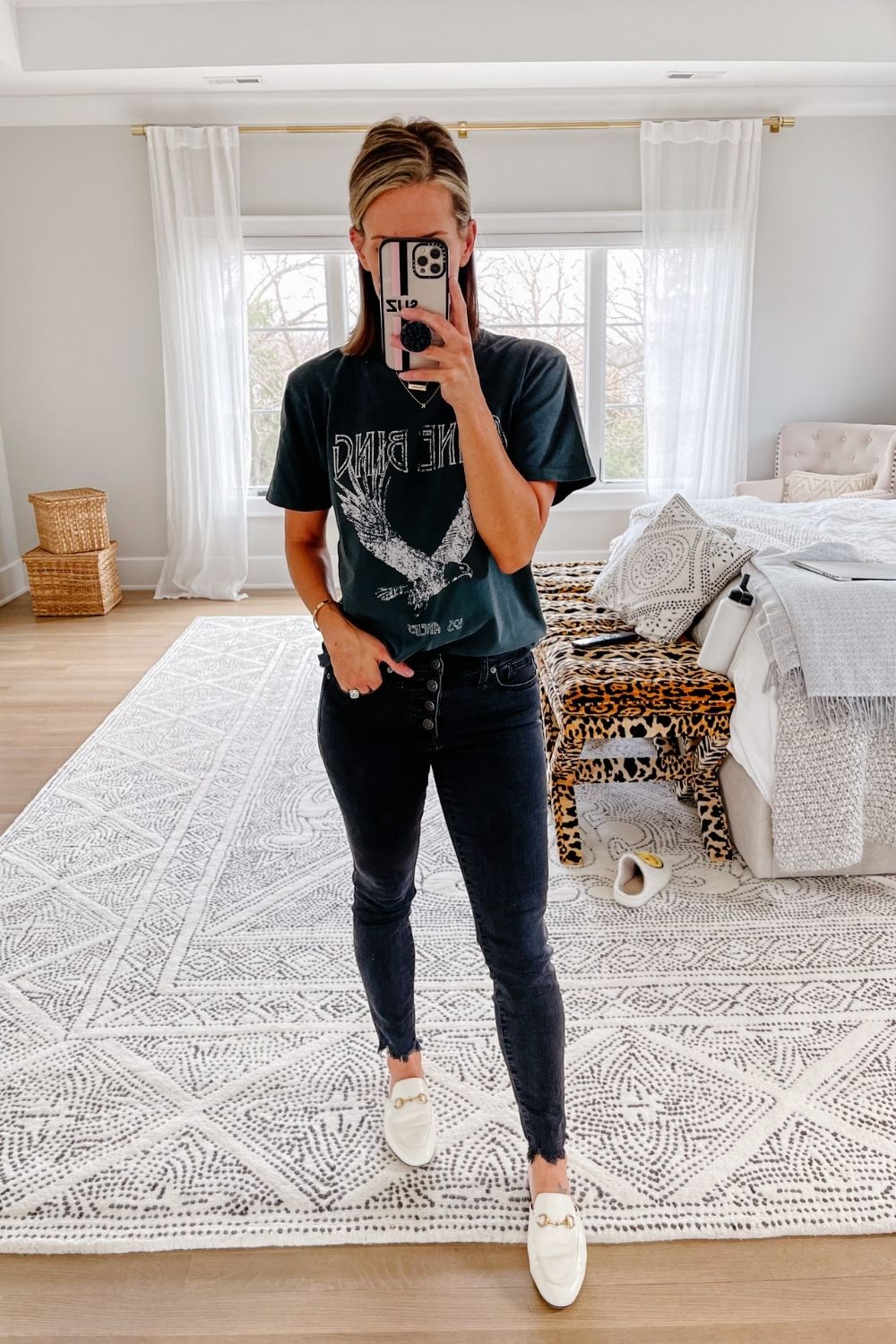 Suzanne wearing a black graphic tee, black denim, and mules