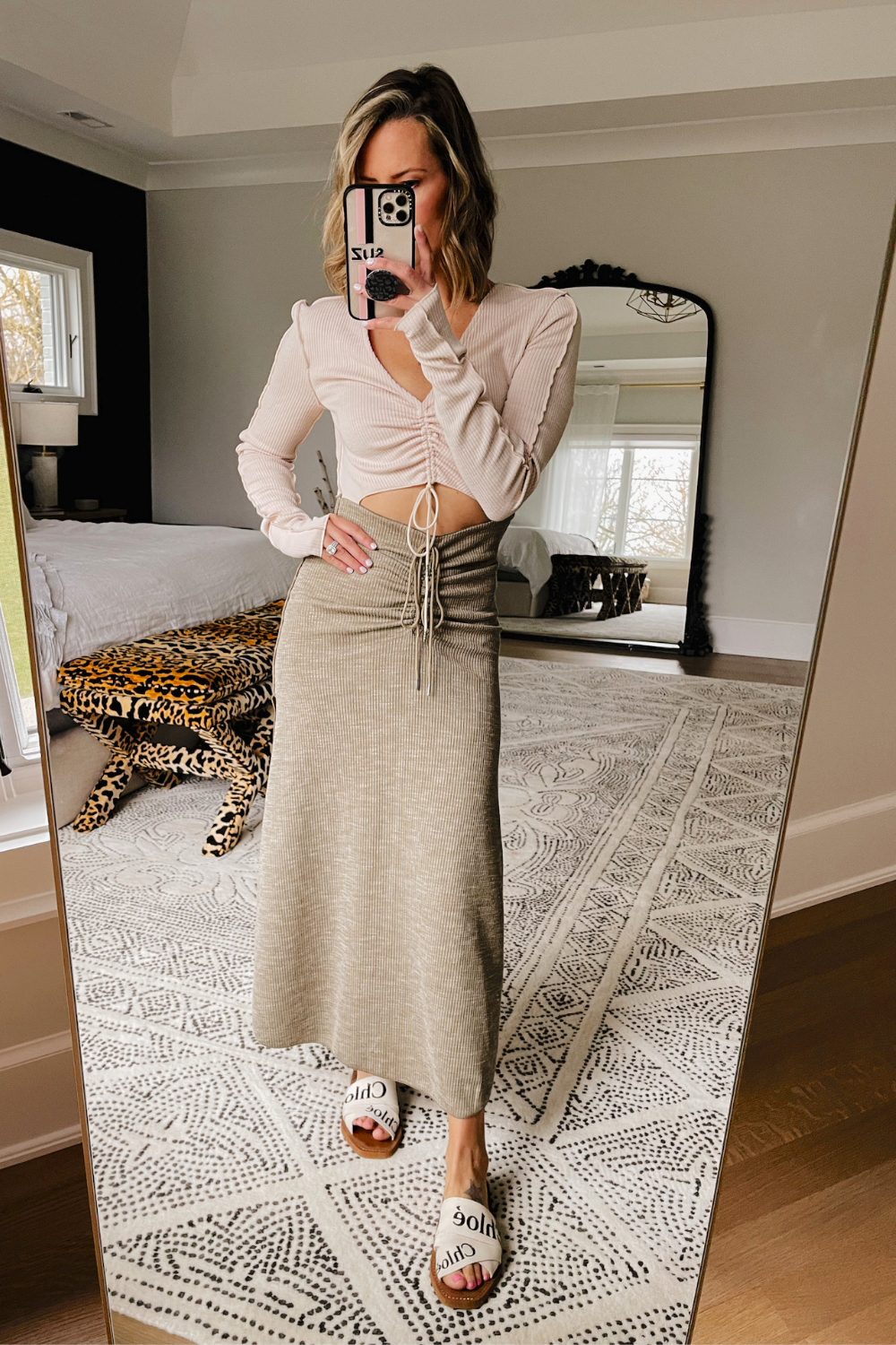 Suzanne taking a mirror selfie wearing a midi dress with cut outs and Chloe sandals. 