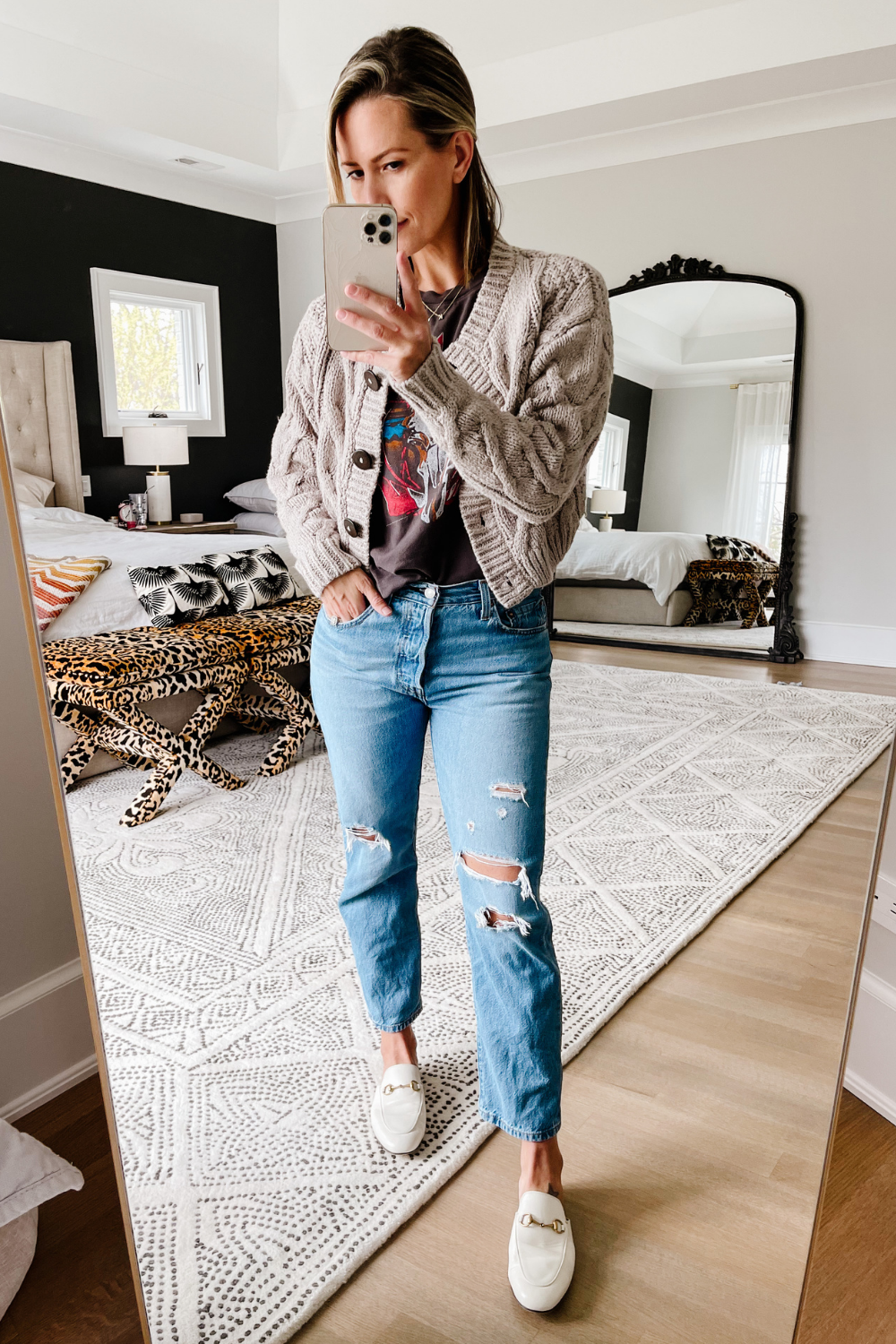 Suzanne wearing a graphic tee, cardigan, and denim jeans