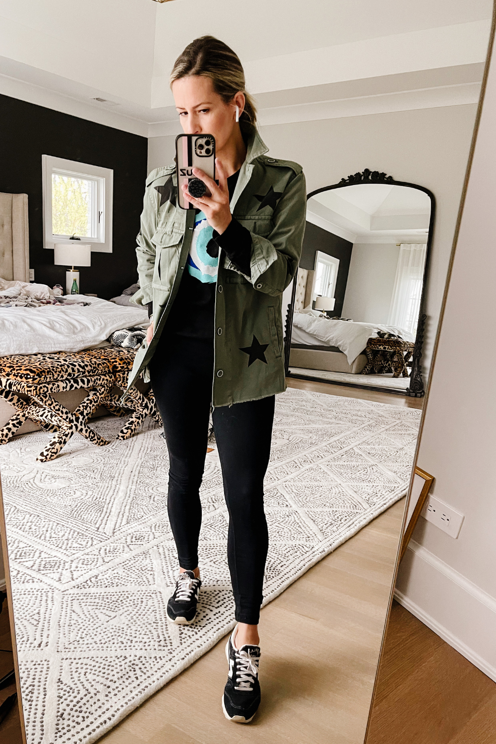 Suzanne wearing a graphic tee, leggings, sneakers, and a star print jacket