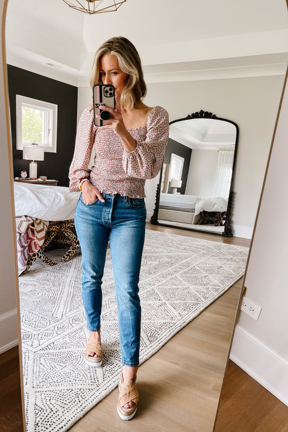 Suzanne wearing a floral square neck top, denim jeans and wedges