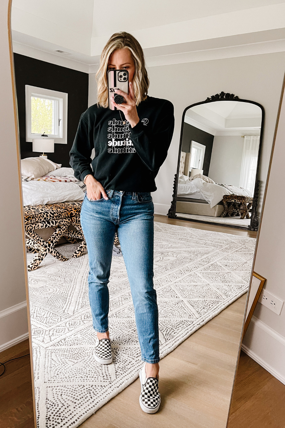 Suzanne wearing a "gratitude" pullover, denim jeans, and Vans