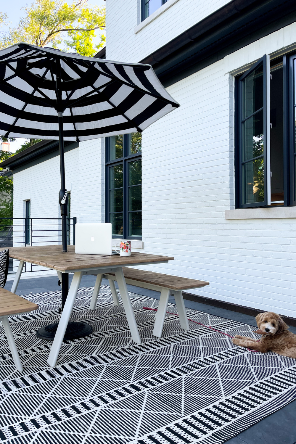 Balcony styling: picnic table, black and white rug, umbrella. Pictured is Suzanne's dog, Georgia