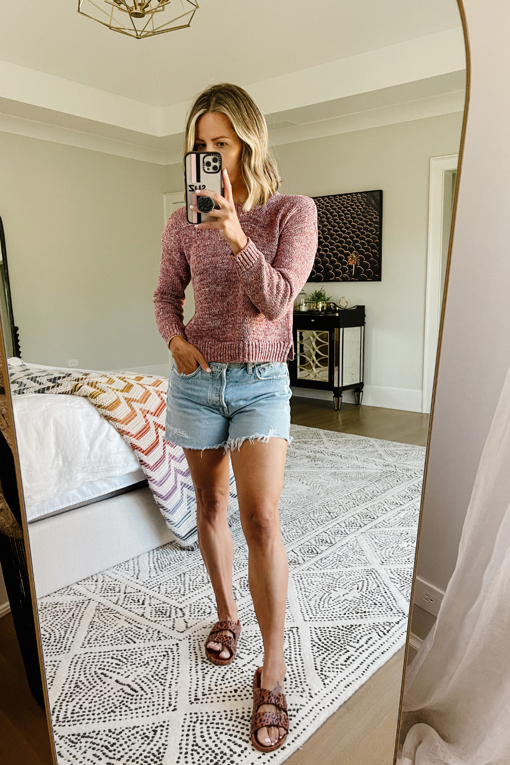 Suzanne wearing a Madewell sweater, AGOLDE shorts, and leopard slides