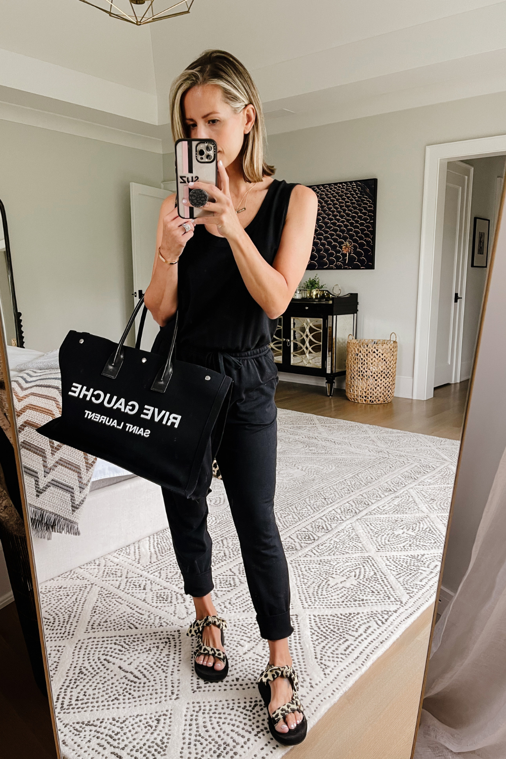 Suzanne wearing a black Amazon jumpsuit, sport sandals, and a tote bag
