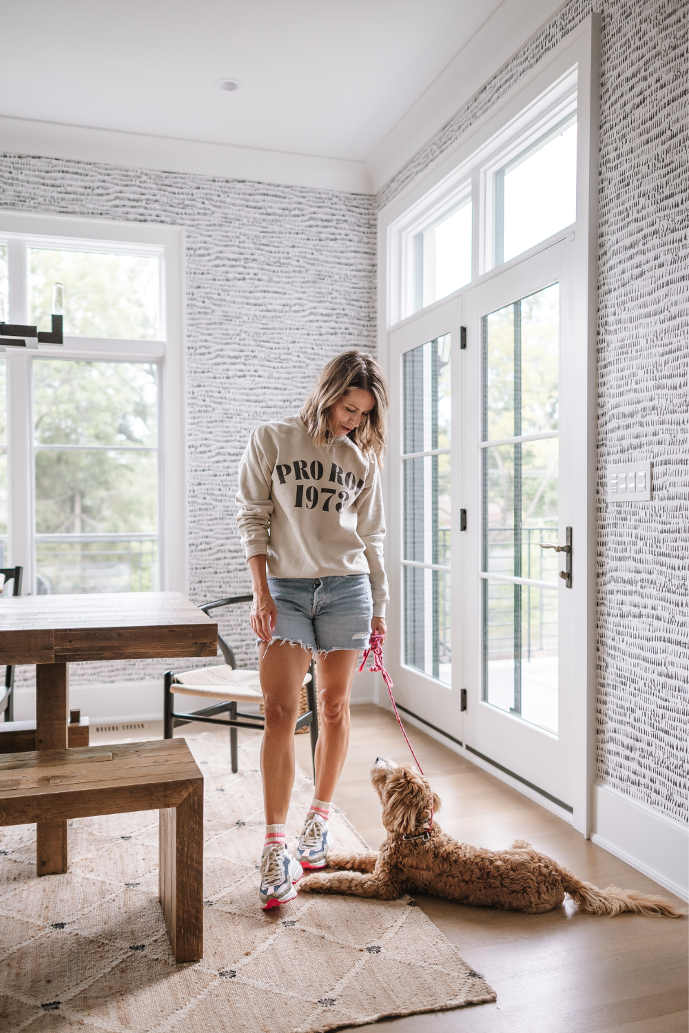 Suzanne wearing a "Pro Roe" sweatshirt in the kitchen nook with her dog, Georgia 