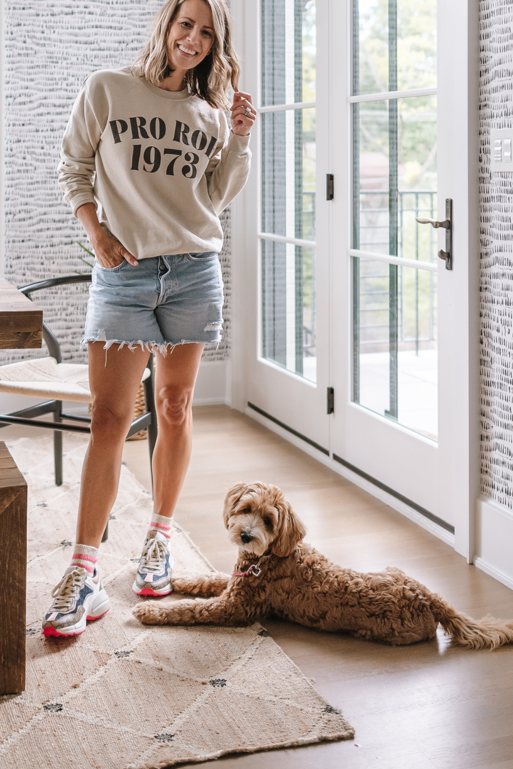 Suzanne wearing a "Pro Roe" sweatshirt in the kitchen nook with her dog, Georgia 