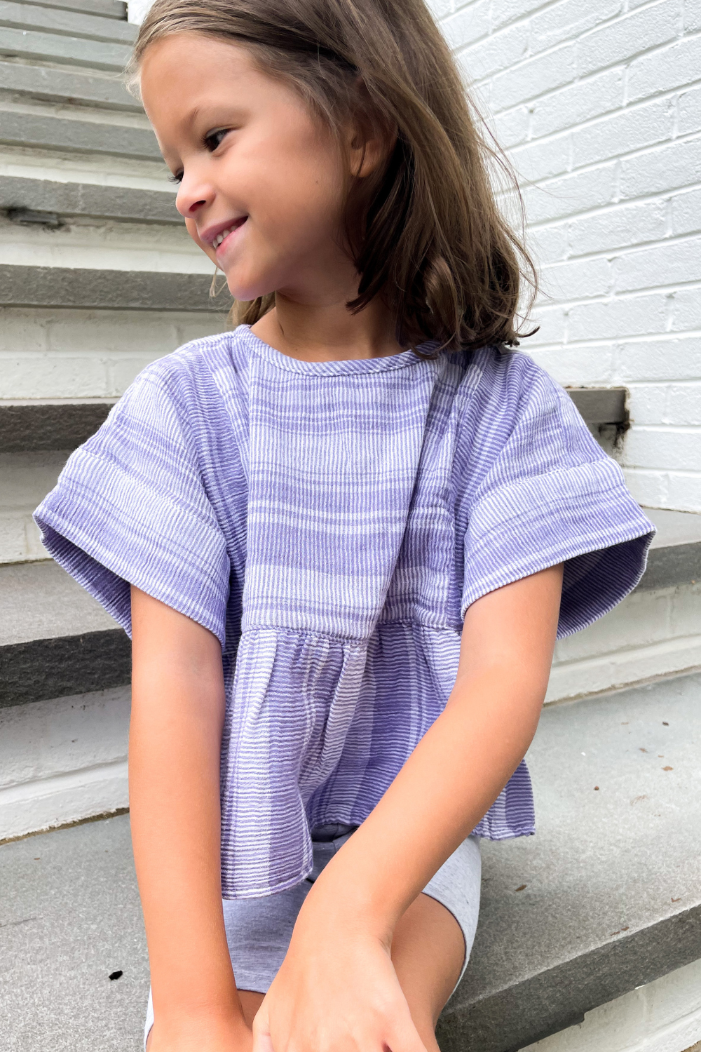 Suzanne's daughter posing in a purple peplum top 