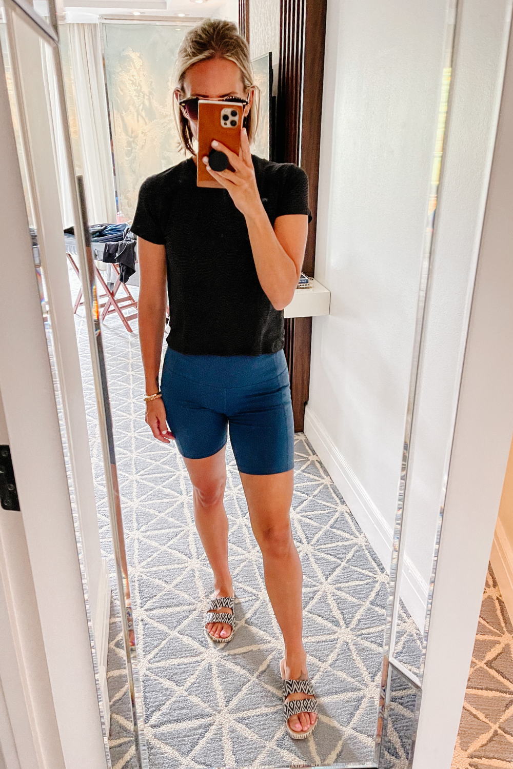 Suzanne in a black t-shirt, biker shorts, and slides