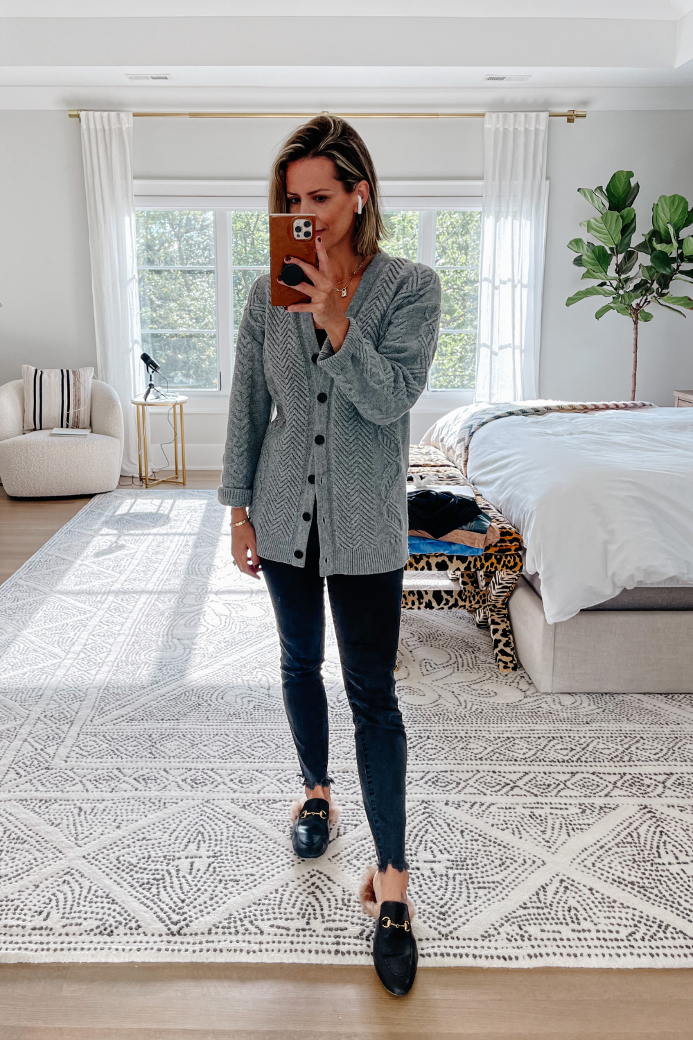Suzanne wearing a grey sweater, black denim, and mules