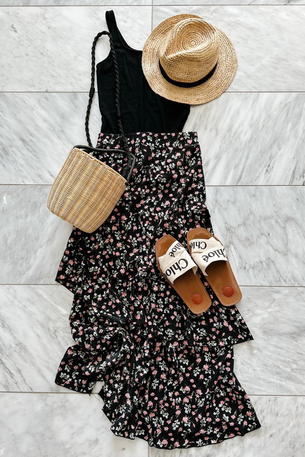 A tank top and floral midi skirt styled with a straw hat, straw bag, and sandals
